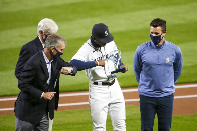 Sep 23, 2020; Seattle, Washington, USA; Seattle Mariners CEO Kevin Mather, left, bumps elbows with center fielder Kyle Lewis (1) after he was presented with the Seattle chapter of the Baseball Writers of America team MVP award before a game against the Houston Astros at T-Mobile Park. Seattle Mariners general manager Jerry Dipoto stands at right. Mandatory Credit: Joe Nicholson-USA TODAY Sports
