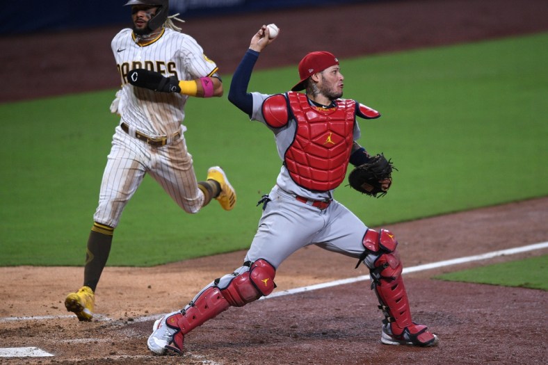 Oct 2, 2020; San Diego, California, USA; St. Louis Cardinals catcher Yadier Molina (right) throws to second base after forcing out San Diego Padres shortstop Fernando Tatis Jr. (left) at home during the seventh inning at Petco Park. Mandatory Credit: Orlando Ramirez-USA TODAY Sports