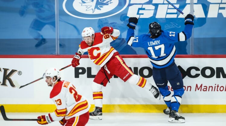 Feb 1, 2021; Winnipeg, Manitoba, CAN;  Calgary Flames defenseman Nikita Nesterov (89) and Winnipeg Jets forward Adam Lowry (17) react to a collision during the first period at Bell MTS Place. Mandatory Credit: Terrence Lee-USA TODAY Sports