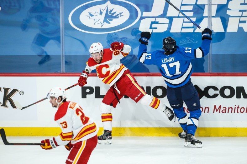 Feb 1, 2021; Winnipeg, Manitoba, CAN;  Calgary Flames defenseman Nikita Nesterov (89) and Winnipeg Jets forward Adam Lowry (17) react to a collision during the first period at Bell MTS Place. Mandatory Credit: Terrence Lee-USA TODAY Sports
