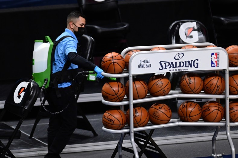 Feb 1, 2021; Denver, Colorado, USA; General view of Ball Arena staff member Antonio Escobedo using disinfectant spray on NBA basketballs following the postponed game between the Detroit Pistons against the Denver Nuggets. Mandatory Credit: Ron Chenoy-USA TODAY