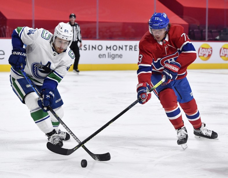 Feb 1, 2021; Montreal, Quebec, CAN; Montreal Canadiens forward Tyler Toffoli (73) plays the puck and Vancouver Canucks forward Tyler Motte (64) defends during the second period at the Bell Centre. Mandatory Credit: Eric Bolte-USA TODAY Sports