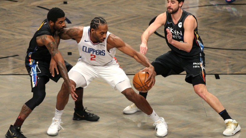 Feb 2, 2021; Brooklyn, New York, USA; Los Angeles Clippers small forward Kawhi Leonard (2) controls the ball against Brooklyn Nets point guard Kyrie Irving (L) and small forward Joe Harris (R) during the first quarter at Barclays Center. Mandatory Credit: Brad Penner-USA TODAY Sports