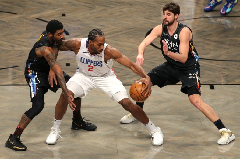 Feb 2, 2021; Brooklyn, New York, USA; Los Angeles Clippers small forward Kawhi Leonard (2) controls the ball against Brooklyn Nets point guard Kyrie Irving (L) and small forward Joe Harris (R) during the first quarter at Barclays Center. Mandatory Credit: Brad Penner-USA TODAY Sports