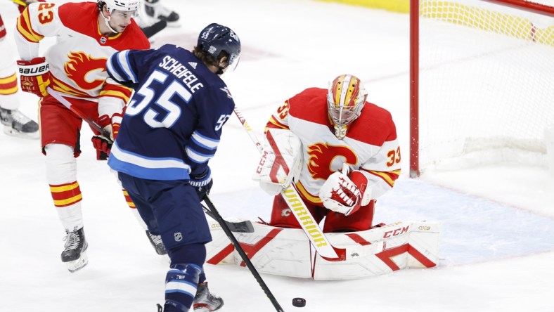 Feb 2, 2021; Winnipeg, Manitoba, CAN.;  Winnipeg Jets center Mark Scheifele (55) looks for a rebound after a shot on Calgary Flames goaltender David Rittich (33) in the second period at Bell MTS Place. Mandatory Credit: James Carey Lauder-USA TODAY Sports