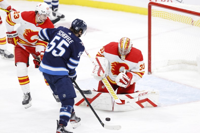 Feb 2, 2021; Winnipeg, Manitoba, CAN.;  Winnipeg Jets center Mark Scheifele (55) looks for a rebound after a shot on Calgary Flames goaltender David Rittich (33) in the second period at Bell MTS Place. Mandatory Credit: James Carey Lauder-USA TODAY Sports