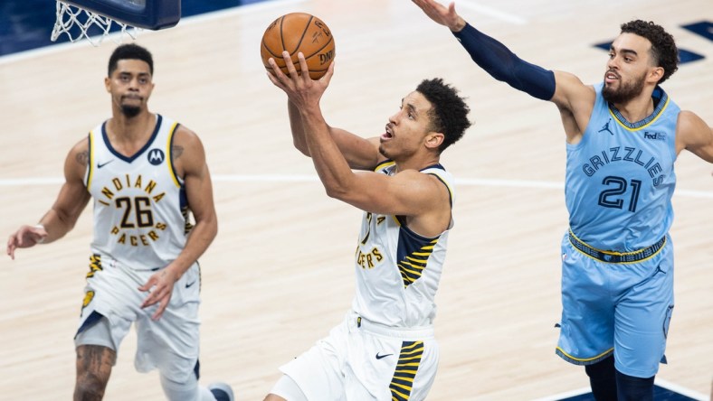 Feb 2, 2021; Indianapolis, Indiana, USA; Indiana Pacers guard Malcolm Brogdon (7) shoots the ball wheel Memphis Grizzlies guard Tyus Jones (21) defends in the third quarter at Bankers Life Fieldhouse. Mandatory Credit: Trevor Ruszkowski-USA TODAY Sports