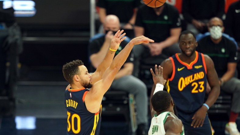 Feb 2, 2021; San Francisco, California, USA; Golden State Warriors guard Stephen Curry (30) hits a 3 pointer over Boston Celtics guard Jaylen Brown (7) during the first quarter at Chase Center. Mandatory Credit: Darren Yamashita-USA TODAY Sports