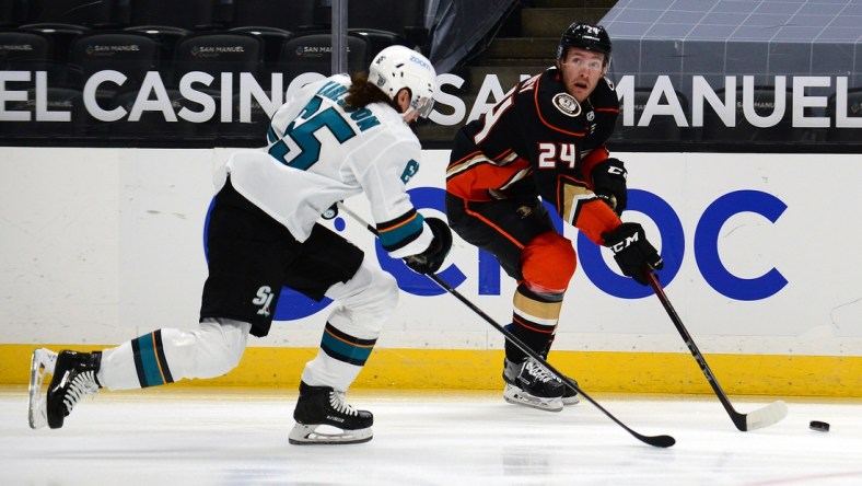 Feb 5, 2021; Anaheim, California, USA; Anaheim Ducks right wing Carter Rowney (24) moves the puck against San Jose Sharks defenseman Erik Karlsson (65) during the first period at Honda Center. Mandatory Credit: Gary A. Vasquez-USA TODAY Sports