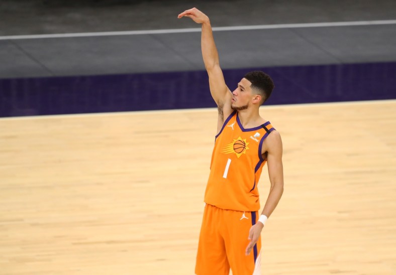 Feb 5, 2021; Phoenix, Arizona, USA; Phoenix Suns guard Devin Booker (1) follows through on a three pointer against the Detroit Pistons in the second half at Phoenix Suns Arena. Mandatory Credit: Mark J. Rebilas-USA TODAY Sports