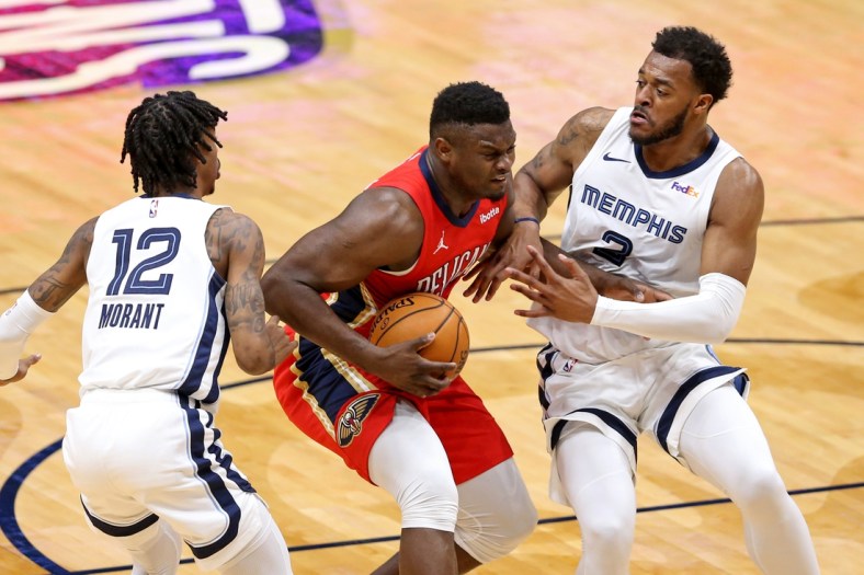 Feb 6, 2021; New Orleans, Louisiana, USA; New Orleans Pelicans forward Zion Williamson (1) is defended by Memphis Grizzlies guard Ja Morant (12) and forward Xavier Tillman (2) in the first quarter at the Smoothie King Center. Mandatory Credit: Chuck Cook-USA TODAY Sports