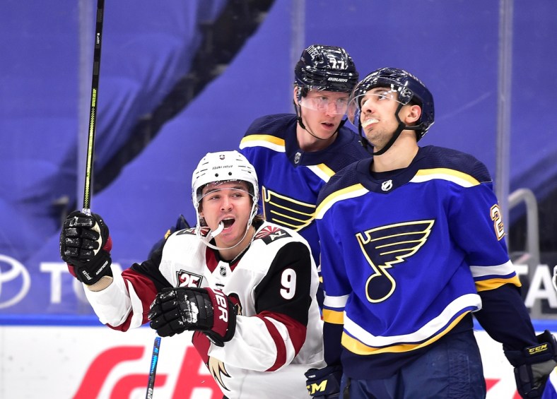 Feb 8, 2021; St. Louis, Missouri, USA;  Arizona Coyotes right wing Clayton Keller (9) celebrates after assisting on a goal as St. Louis Blues center Jordan Kyrou (25) reacts at Enterprise Center. Mandatory Credit: Jeff Curry-USA TODAY Sports