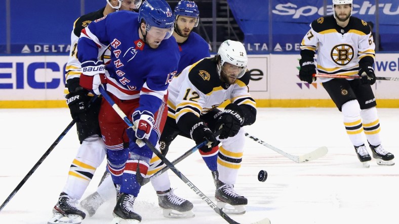 Feb 10, 2021; New York, New York, USA;  Alexis Lafreniere #13 of the New York Rangers and Craig Smith #12 of the Boston Bruins battle for the puck during the first period at Madison Square Garden. Mandatory Credit: Bruce Bennett/Pool Photo-USA TODAY Sports