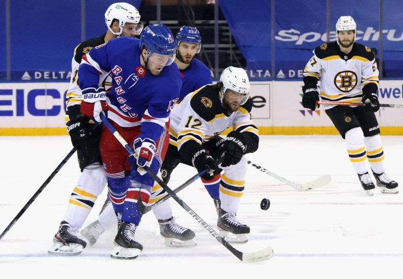 Feb 10, 2021; New York, New York, USA;  Alexis Lafreniere #13 of the New York Rangers and Craig Smith #12 of the Boston Bruins battle for the puck during the first period at Madison Square Garden. Mandatory Credit: Bruce Bennett/Pool Photo-USA TODAY Sports