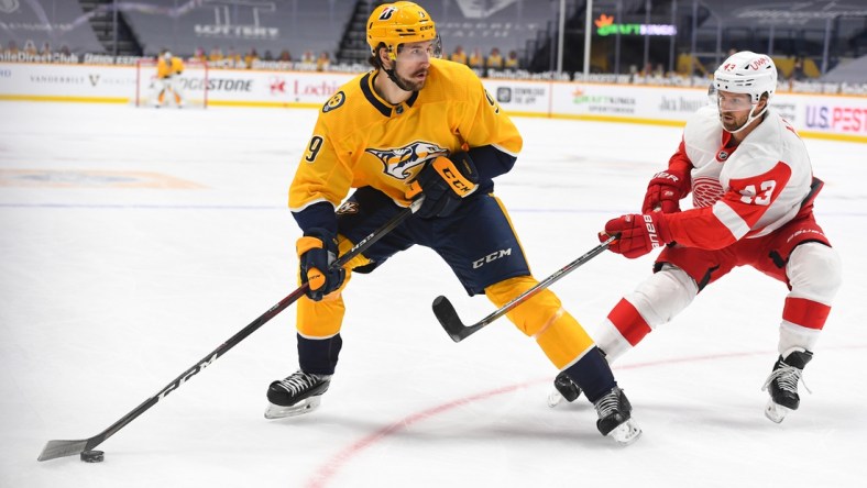 Feb 11, 2021; Nashville, Tennessee, USA; Nashville Predators left wing Filip Forsberg (9) looks to pass the puck as he is defended by Detroit Red Wings left wing Darren Helm (43) during the first period at Bridgestone Arena. Mandatory Credit: Christopher Hanewinckel-USA TODAY Sports