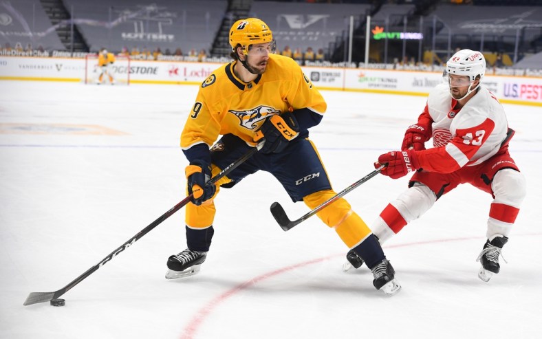 Feb 11, 2021; Nashville, Tennessee, USA; Nashville Predators left wing Filip Forsberg (9) looks to pass the puck as he is defended by Detroit Red Wings left wing Darren Helm (43) during the first period at Bridgestone Arena. Mandatory Credit: Christopher Hanewinckel-USA TODAY Sports