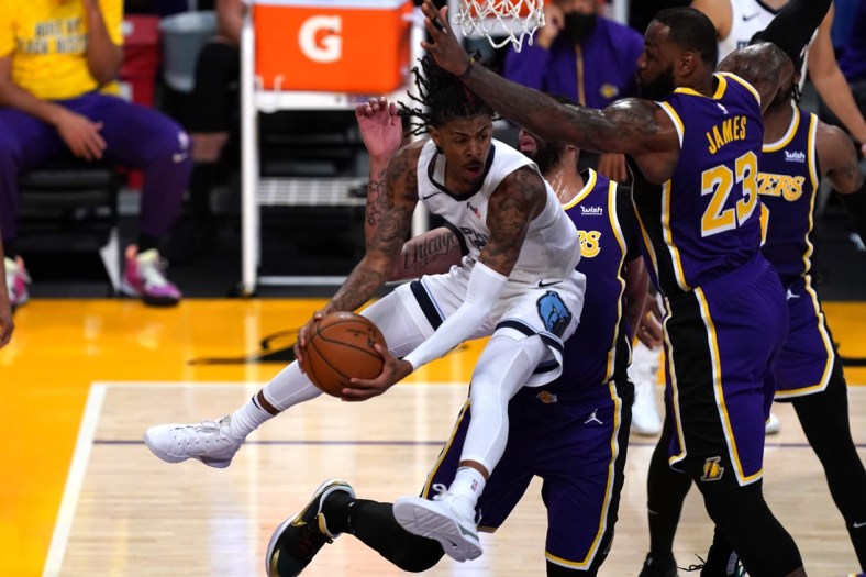 Feb 12, 2021; Los Angeles, California, USA; Memphis Grizzlies guard Ja Morant (12) is defended by Los Angeles Lakers forward Anthony Davis (3) and forward LeBron James (23) in the first half at Staples Center. Mandatory Credit: Kirby Lee-USA TODAY Sports