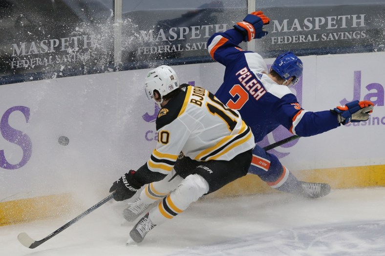 Feb 13, 2021; Uniondale, New York, USA; Boston Bruins left wing Anders Bjork (10) and New York Islanders defenseman Adam Pelech (3) chase a loose puck during the first period at Nassau Veterans Memorial Coliseum. Mandatory Credit: Brad Penner-USA TODAY Sports