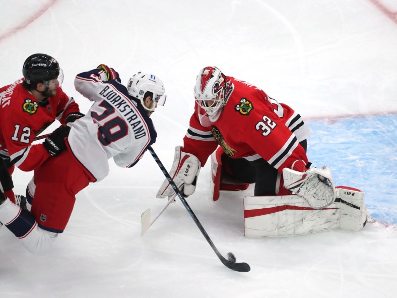Feb 13, 2021; Chicago, Illinois, USA; Columbus Blue Jackets right wing Oliver Bjorkstrand (28) shoots on Chicago Blackhawks goaltender Kevin Lankinen (32) with  left wing Alex DeBrincat (12) defending during the first period at the United Center. Mandatory Credit: Dennis Wierzbicki-USA TODAY Sports