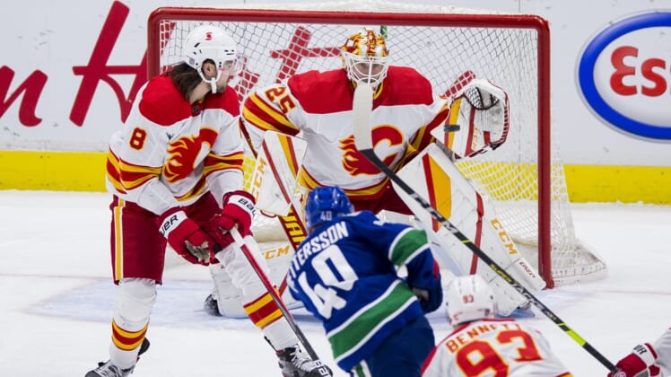 Feb 13, 2021; Vancouver, British Columbia, CAN; Calgary Flames goalie Jacob Markstrom (25) makes a save against Vancouver Canucks forward Elias Pettersson (40) as Calgary defenseman Christopher Tanev (8) looks on in the third period at Rogers Arena. Vancouver won 3-1. Mandatory Credit: Bob Frid-USA TODAY Sports
