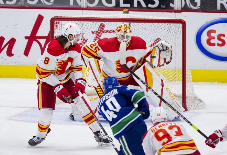 Feb 13, 2021; Vancouver, British Columbia, CAN; Calgary Flames goalie Jacob Markstrom (25) makes a save against Vancouver Canucks forward Elias Pettersson (40) as Calgary defenseman Christopher Tanev (8) looks on in the third period at Rogers Arena. Vancouver won 3-1. Mandatory Credit: Bob Frid-USA TODAY Sports