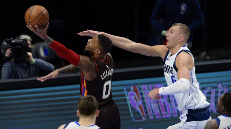 Feb 14, 2021; Dallas, Texas, USA; Portland Trail Blazers guard Damian Lillard (0) drives to the basket past Dallas Mavericks center Kristaps Porzingis (6) during the first quarter at the American Airlines Center. Mandatory Credit: Jerome Miron-USA TODAY Sports