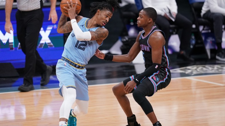 Feb 14, 2021; Sacramento, California, USA; Memphis Grizzlies guard Ja Morant (12) holds onto the ball next to Sacramento Kings guard De'Aaron Fox (5) in the second quarter at the Golden 1 Center. Mandatory Credit: Cary Edmondson-USA TODAY Sports