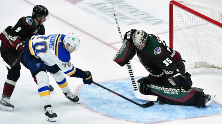 Feb 15, 2021; Glendale, Arizona, USA;  St. Louis Blues center Oskar Sundqvist (70) reaches for the puck as Arizona Coyotes right wing Clayton Keller (9) and goaltender Darcy Kuemper (35) defend during the second period at Gila River Arena. Mandatory Credit: Matt Kartozian-USA TODAY Sports