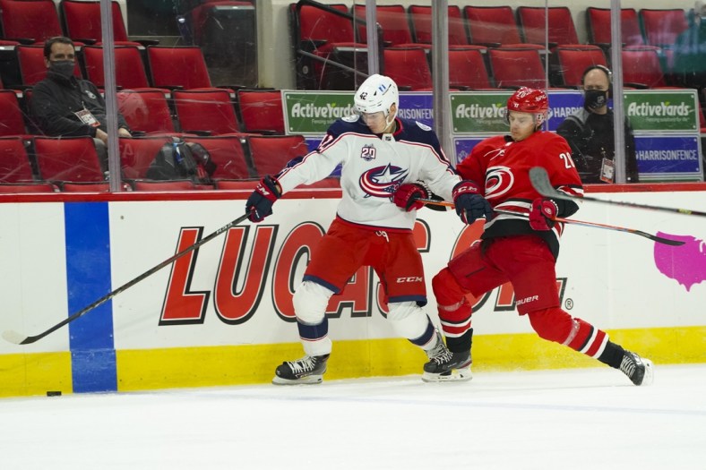 Feb 15, 2021; Raleigh, North Carolina, USA; Columbus Blue Jackets center Alexandre Texier (42) and Carolina Hurricanes right wing Sebastian Aho (20) chase after the puck during the first period at PNC Arena. Mandatory Credit: James Guillory-USA TODAY Sports