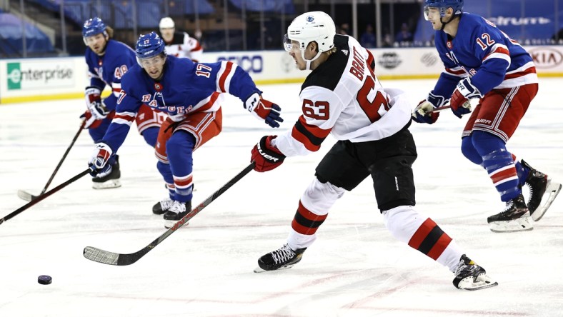 Feb 16, 2021; New York, New York, USA;  Jesper Bratt #63 of the New Jersey Devils takes a shot as Kevin Rooney #17 and Julien Gauthier #12 of the New York Rangers defend during the first period at Madison Square Garden. Mandatory Credit:  Elsa/POOL PHOTOS-USA TODAY Sports