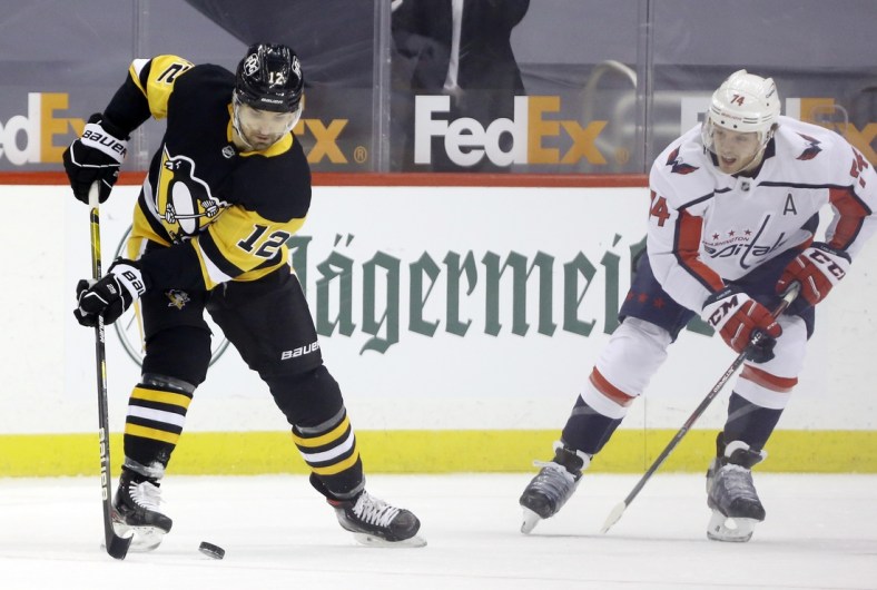 Feb 14, 2021; Pittsburgh, Pennsylvania, USA;  Pittsburgh Penguins center Zach Aston-Reese (12) handles the puck against Washington Capitals defenseman John Carlson (74) during the first period at PPG Paints Arena. Pittsburgh won 6-3. Mandatory Credit: Charles LeClaire-USA TODAY Sports