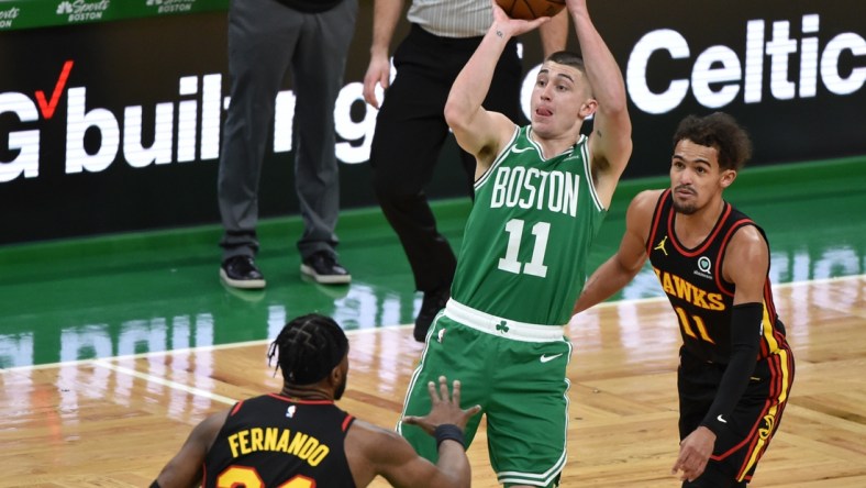 Feb 17, 2021; Boston, Massachusetts, USA; Boston Celtics guard Payton Pritchard (11) shoots the ball while defended by Atlanta Hawks forward Bruno Fernando (24) and guard Trae Young (11) during the first half at TD Garden. Mandatory Credit: Bob DeChiara-USA TODAY Sports