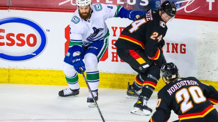 Feb 17, 2021; Calgary, Alberta, CAN; Vancouver Canucks defenseman Jordie Benn (8) and Calgary Flames right wing Brett Ritchie (24) battle for the puck during the first period at Scotiabank Saddledome. Mandatory Credit: Sergei Belski-USA TODAY Sports