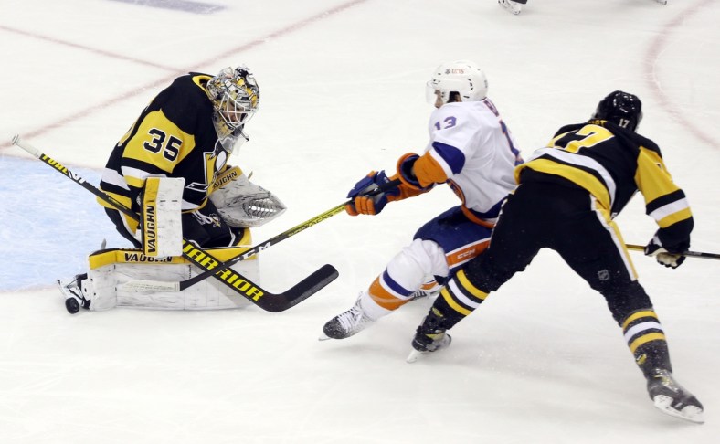 Feb 18, 2021; Pittsburgh, Pennsylvania, USA; Pittsburgh Penguins goaltender Tristan Jarry (35) makes a save against New York Islanders center Mathew Barzal (13) as Pens right wing Bryan Rust (17) defends during the first period at PPG Paints Arena. Mandatory Credit: Charles LeClaire-USA TODAY Sports