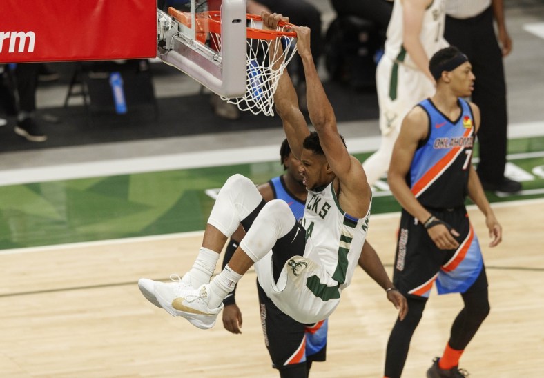 Feb 19, 2021; Milwaukee, Wisconsin, USA;  Milwaukee Bucks forward Giannis Antetokounmpo (34) hangs from the rim following a dunk during the third quarter against the Oklahoma City Thunder at Fiserv Forum. Mandatory Credit: Jeff Hanisch-USA TODAY Sports