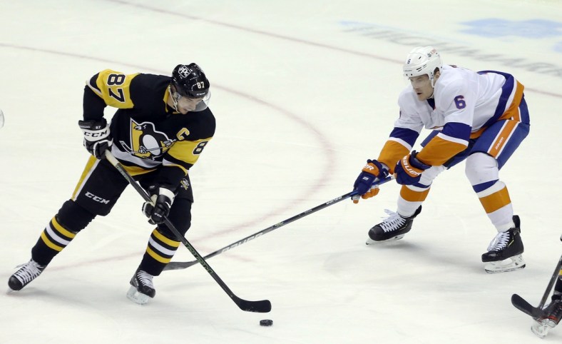 Feb 20, 2021; Pittsburgh, Pennsylvania, USA;  Pittsburgh Penguins center Sidney Crosby (87) handles the puck as New York Islanders defenseman Ryan Pulock (6) defends during the first period at PPG Paints Arena. Mandatory Credit: Charles LeClaire-USA TODAY Sports