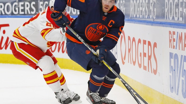 Feb 20, 2021; Edmonton, Alberta, CAN; Edmonton Oilers forward Connor McDavid (97) moves the puck past Calgary Flames forward Elias Lindholm (28) during the first period at Rogers Place. Mandatory Credit: Perry Nelson-USA TODAY Sports