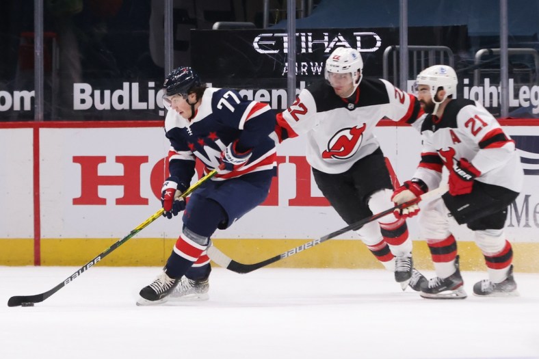 Feb 21, 2021; Washington, District of Columbia, USA; Washington Capitals right wing T.J. Oshie (77) skates with the puck as New Jersey Devils defenseman Ryan Murray (22) and Devils right wing Kyle Palmieri (21) chase in the first period at Capital One Arena. Mandatory Credit: Geoff Burke-USA TODAY Sports