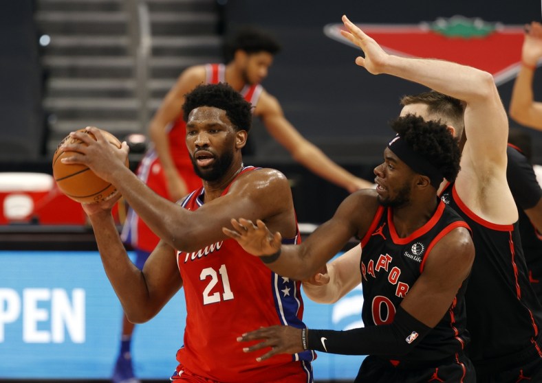 Feb 21, 2021; Tampa, Florida, USA; Philadelphia 76ers center Joel Embiid (21) drives to the basket as Toronto Raptors guard Terence Davis (0) defends during the first quarter at Amalie Arena. Mandatory Credit: Kim Klement-USA TODAY Sports