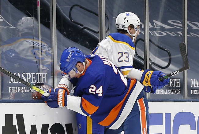 Feb 22, 2021; Uniondale, New York, USA; New York Islanders defenseman Scott Mayfield (24) and Buffalo Sabres center Sam Reinhart (23) come together at the boards during the first period at Nassau Veterans Memorial Coliseum. Mandatory Credit: Andy Marlin-USA TODAY Sports