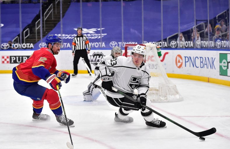 Feb 22, 2021; St. Louis, Missouri, USA;  Los Angeles Kings defenseman Tobias Bjornfot (33) handles the puck as St. Louis Blues left wing Zach Michael Sanford (12) defends during the first period at Enterprise Center. Mandatory Credit: Jeff Curry-USA TODAY Sports