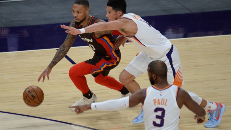 Feb 22, 2021; Phoenix, Arizona, USA; Portland Trail Blazers guard Damian Lillard (0) dribbles against Phoenix Suns guard Devin Booker (1) during the first half at Phoenix Suns Arena. Mandatory Credit: Joe Camporeale-USA TODAY Sports