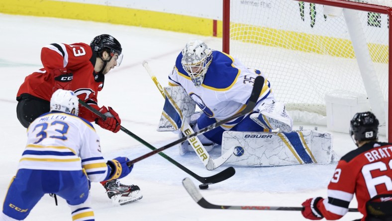 Feb 23, 2021; Newark, New Jersey, USA; New Jersey Devils center Nico Hischier (13) skates with the puck toward Buffalo Sabres goaltender Linus Ullmark (35) during the second period at Prudential Center. Mandatory Credit: Vincent Carchietta-USA TODAY Sports