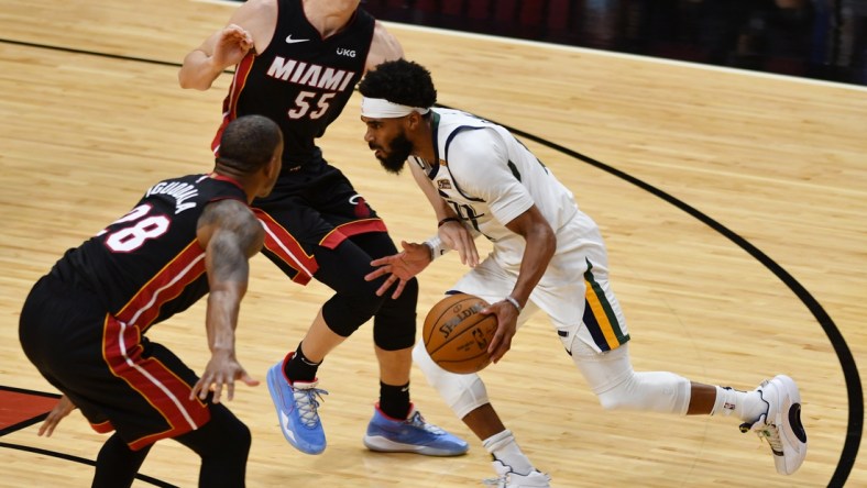 Feb 26, 2021; Miami, Florida, USA; Utah Jazz guard Mike Conley (10) splits the defense of Miami Heat guard Duncan Robinson (55) and forward Andre Iguodala (28) in the first quarter at American Airlines Arena. Mandatory Credit: Jim Rassol-USA TODAY Sports