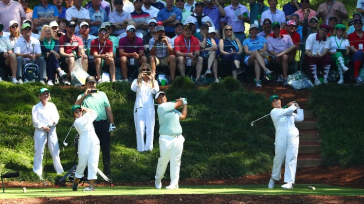 Apr 10, 2019; Augusta, GA, USA; Kiradech Aphibarnrat of Thailand (center) hits his tee shot with two guests during the Par 3 Contest at Augusta National Golf Club. Mandatory Credit: Rob Schumacher-USA TODAY Sports