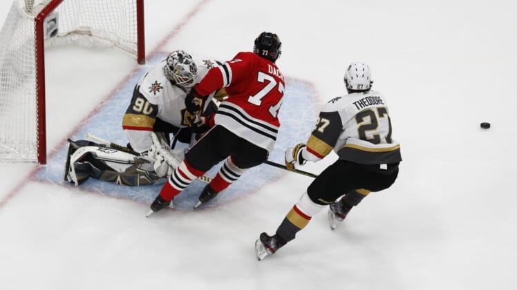 Aug 16, 2020; Edmonton, Alberta, CAN; Chicago Blackhawks center Kirby Dach (77) skates for the puck between Vegas Golden Knights defenseman Shea Theodore (27) and goaltender Robin Lehner (90) during the second period in game four of the first round of the 2020 Stanley Cup Playoffs at Rogers Place. Mandatory Credit: Perry Nelson-USA TODAY Sports