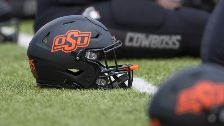 Oct 31, 2020; Stillwater, Oklahoma, USA;  Oklahoma State Cowboys helmets lie on the field as players stretch before a game against the Texas Longhorns at Boone Pickens Stadium. Mandatory Credit: Brett Rojo-USA TODAY Sports