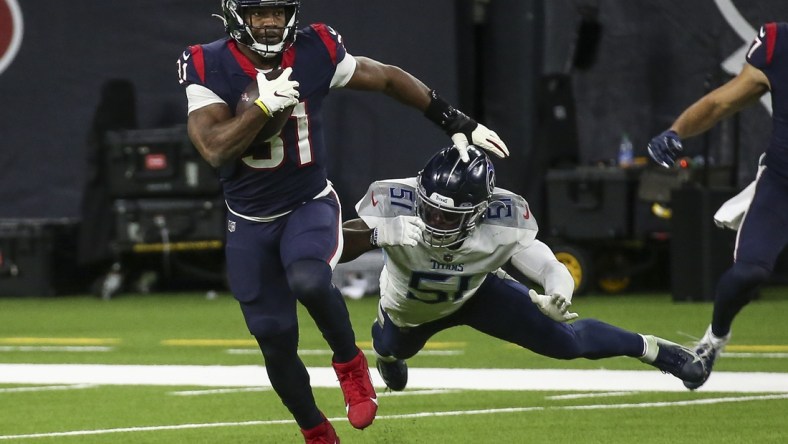 Jan 3, 2021; Houston, Texas, USA; Houston Texans running back David Johnson (31) runs with the ball as Tennessee Titans linebacker David Long (51) attempts to make a tackle during the fourth quarter at NRG Stadium. Mandatory Credit: Troy Taormina-USA TODAY Sports