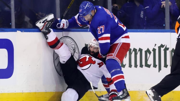 Jan 19, 2021; New York, New York, USA; New York Rangers defenseman Jack Johnson (27) checks New Jersey Devils right wing Kyle Palmieri (21) during the second period at Madison Square Garden. Mandatory Credit:  Bruce Bennett/Pool Photos-USA TODAY Sports