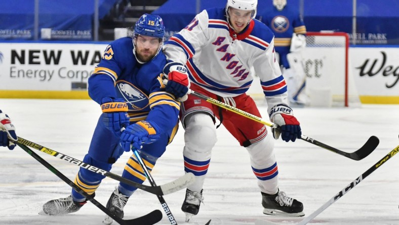 Jan 28, 2021; Buffalo, New York, USA; Buffalo Sabres center Riley Sheahan (15) and New York Rangers center Brett Howden (21) reach for the puck in the second period at KeyBank Center. Mandatory Credit: Mark Konezny-USA TODAY Sports